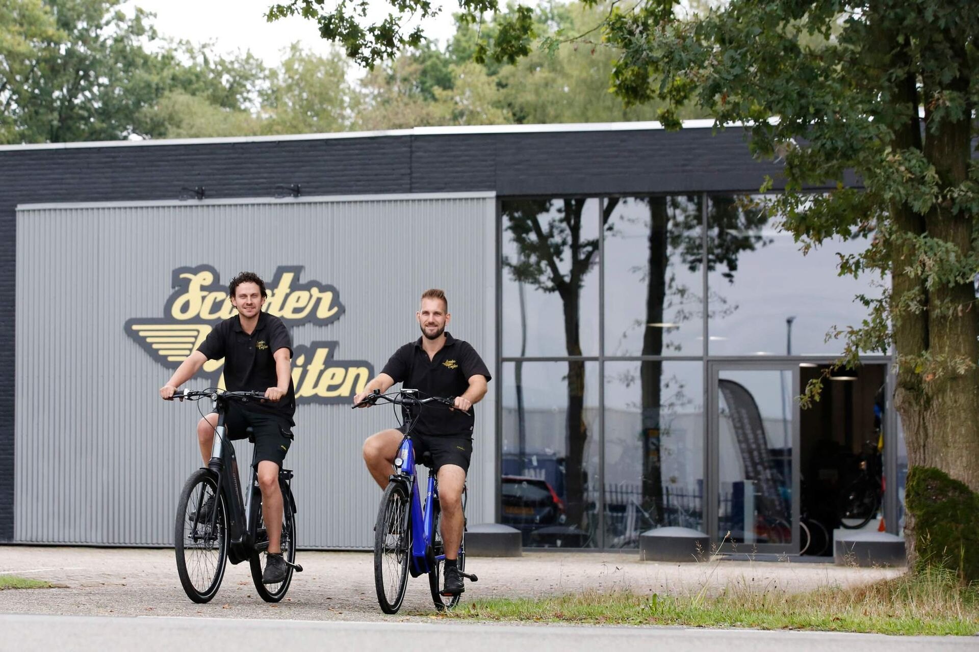 Twee medewerkers van Cuijten fietsen voor het pand in Valkenswaard