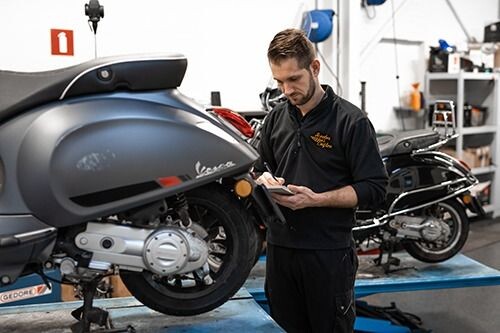 Monteur werkt aan een Vespa in de werkplaats van Cuijten