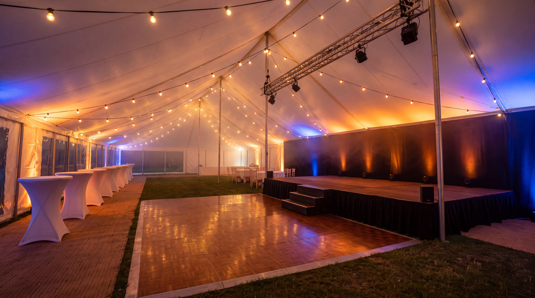 Podium met trap en parketten dansvloer in een verlichte feesttent