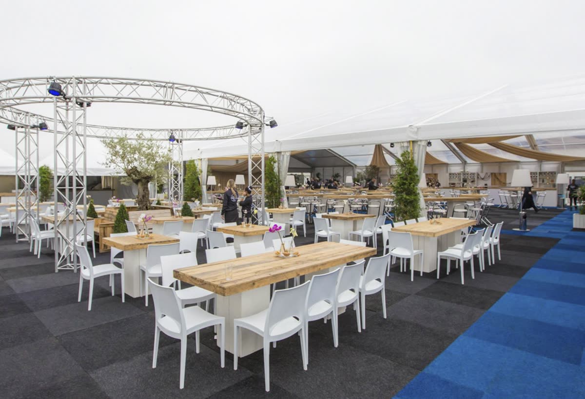 Grote zaal met lange gedekte tafels en trussverlichting