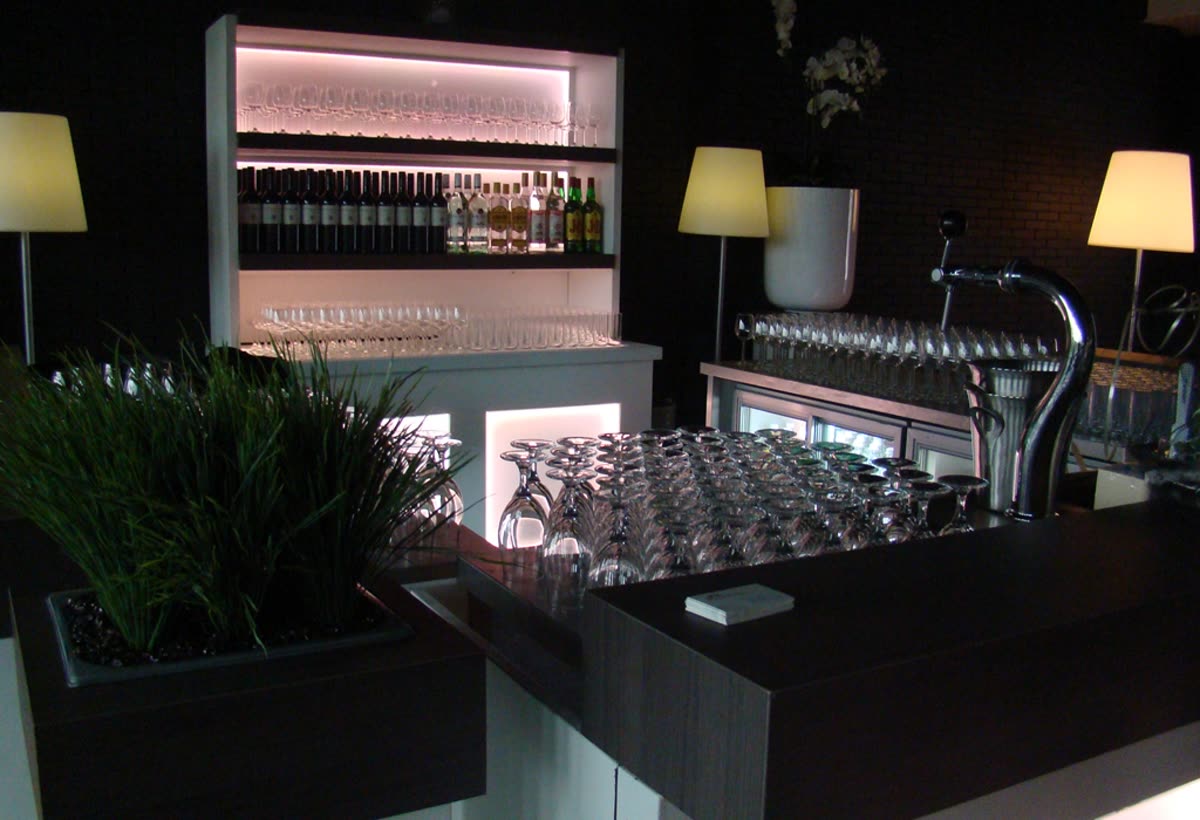 Verlichte bar met flessenwand en rijen schone glazen