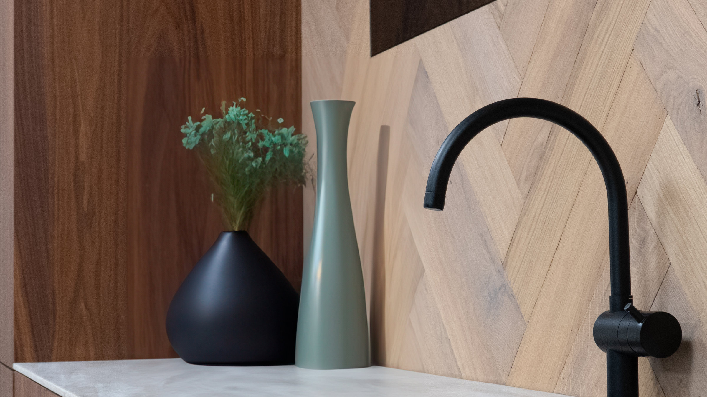 Keuken van ZW Interieur met visgraat in noten, marmeren blad en zwarte kraan