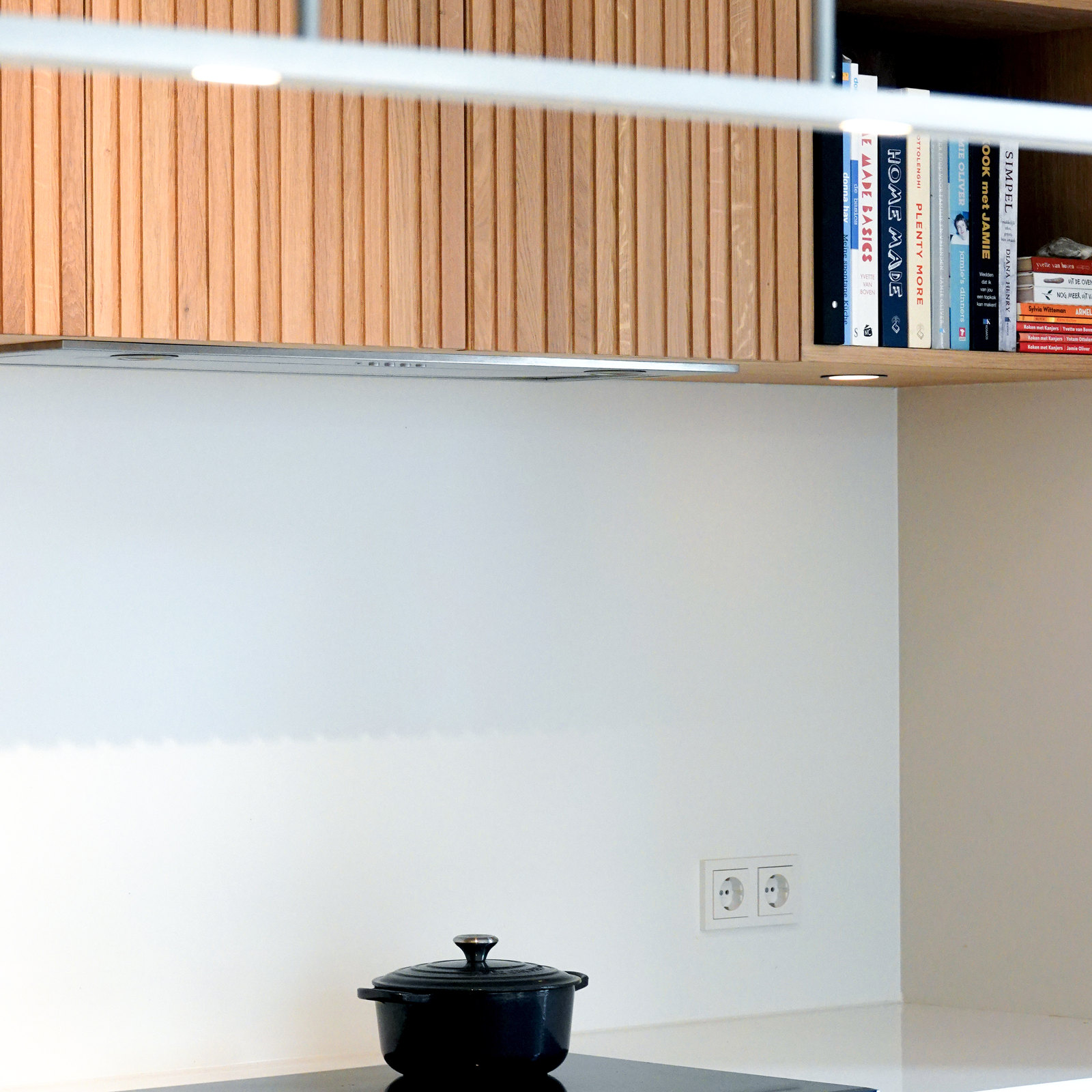 Keuken met notenhouten bovenkasten, wit blad en blauwe wand